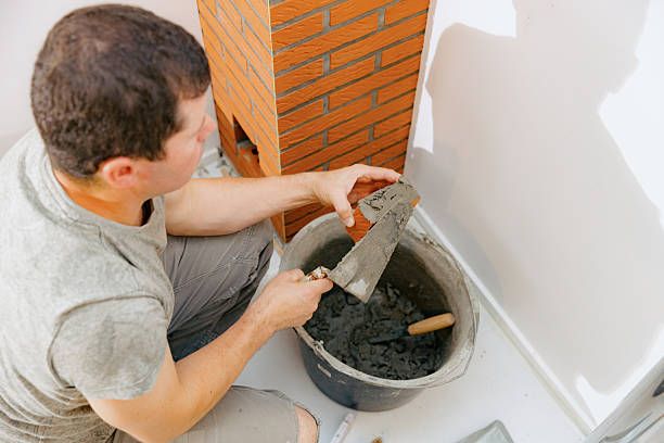 Mason restoring an indoor brick fireplace and hearth in Los Alamitos